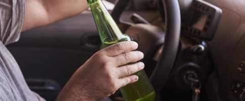 мужчина с алкоголем за рулем машины